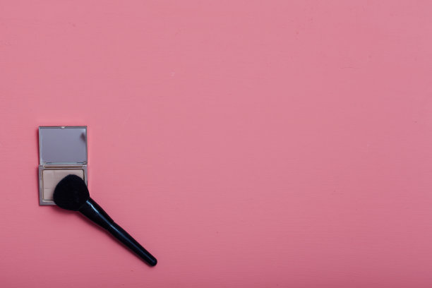 化妆师在粉红色的背景上涂上口红图片下载