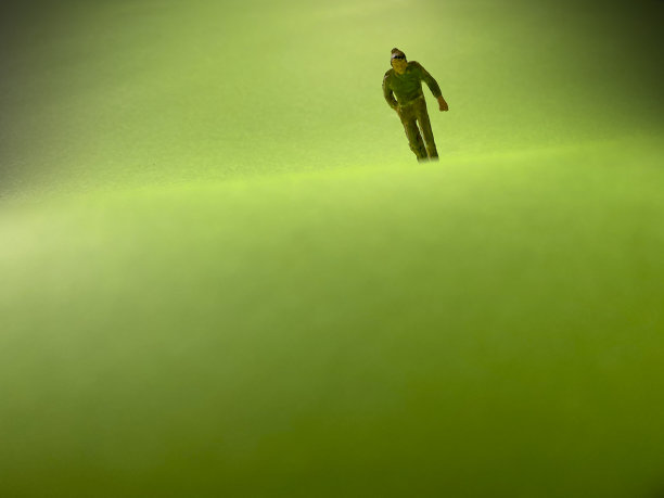 一个微型世界。天空背景上的绿草。纸模型在孤独的概念，微型人物图片下载