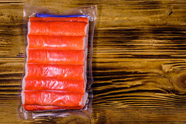 真空包装的蟹棒放在一张木桌上。俯视图图片下载