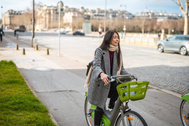 在城市中使用电动自行车的亚洲女性图片下载