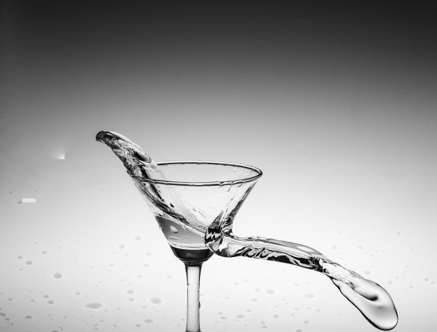 黑白泼水在玻璃杯中，通过泼水在背景中图片下载