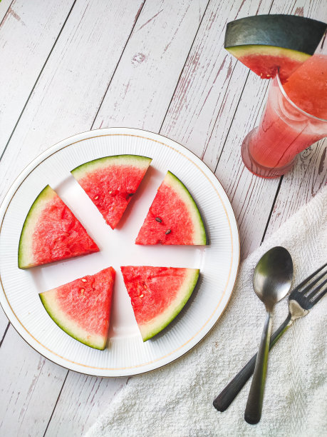 切片西瓜在白色盘子与勺子和叉子股票照片与白色背景。图片下载