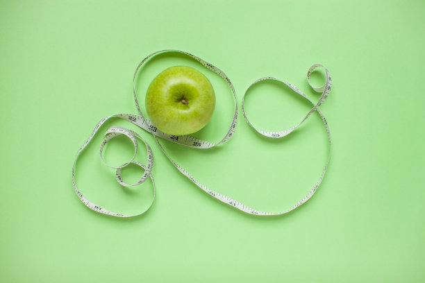 饮食与健康的饮食观念。俯视图的减肥。青苹果和卷尺。绿色背景图片下载
