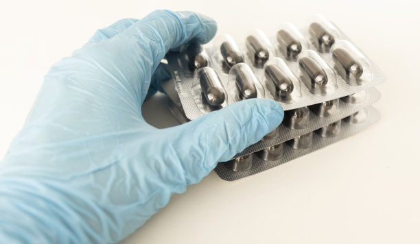 男性的手在一个医疗手套拿着一把黄色药丸。孤立在白色照片上。图片下载