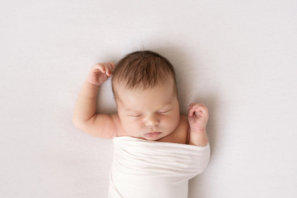 刚出生的婴儿在白色的背景上张开双臂睡觉图片下载