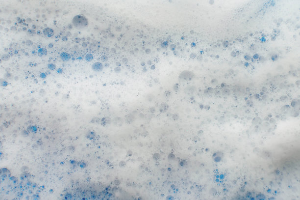 肥皂泡沫的质地在淡紫色的背景上从上面流下来。卫生的概念。图片下载