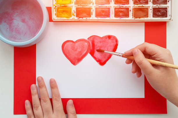 孩子的手在一张白色的纸上用水彩画了一颗心。这就是初恋的概念。图片下载