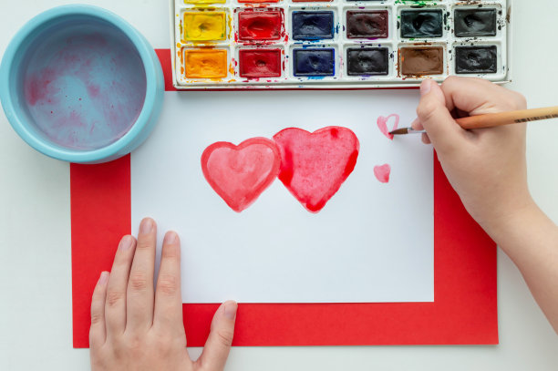 孩子的手在一张白色的纸上用水彩画了一颗心。这就是初恋的概念。图片下载