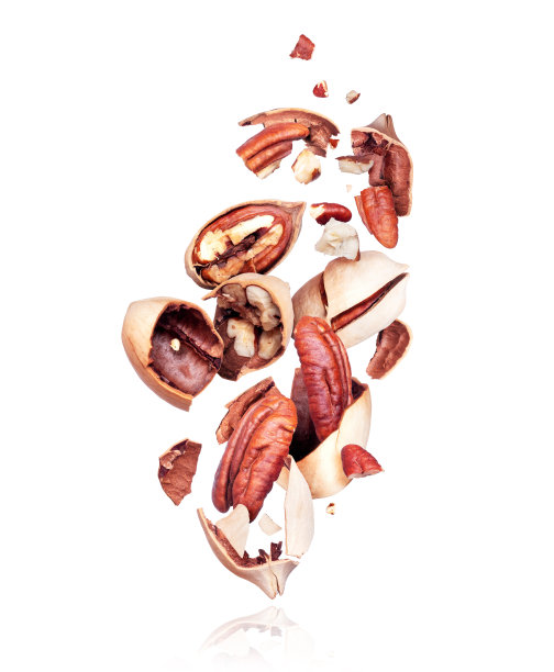 山核桃碎在空气中靠近白色的背景图片下载