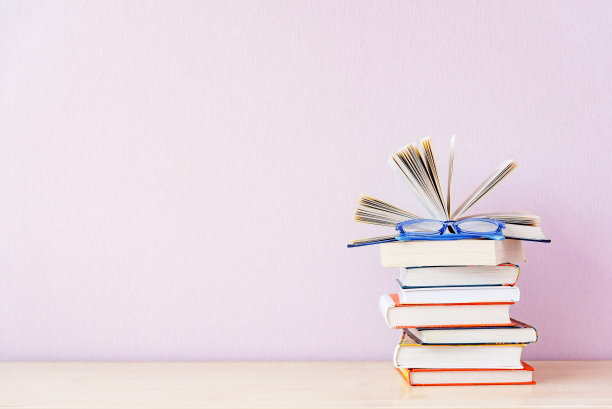 许多书和蓝色眼镜在简单的淡紫色背景。为你的文本复制空间。图片下载