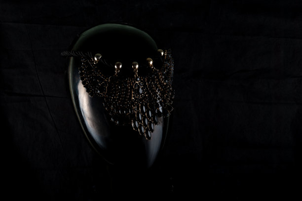 一条以不寻常的方式手工制作的项链呈现了一个女性肖像模特。在黑暗的背景和突出的背后，项链闪闪发光。反射。不是宝石或金属图片下载