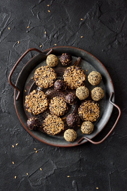 健康的生素食零食。自制的饼干和球与亚麻籽在金属托盘黑色背景复制空间。图片下载