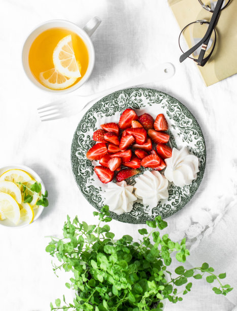 新鲜的草莓，蛋白糖霜，绿茶与柠檬，书舒适的家静物在一个轻的背景，俯视图图片下载