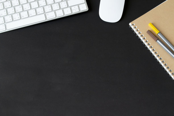 现代黑色办公桌，桌子上配有键盘和鼠标等用品，空白笔记本页中间供输入文本。俯视图，平放。图片下载