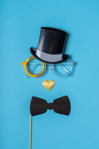 各种黑色照相亭道具:圆柱帽、眼镜、蝴蝶结、蓝底心形鼻子。父亲节贺卡。极简风格的创造性构图图片下载