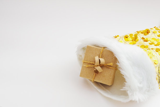 礼盒包装在牛皮纸和捆绑麻绳在黄色圣诞袜在白色的背景图片下载