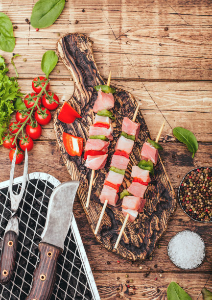 切菜板上的生猪肉串配辣椒粉和新鲜蔬菜，木质背景下用刀叉用一次性木炭烧烤。盐和胡椒，生菜和辣椒粉。俯视图图片下载