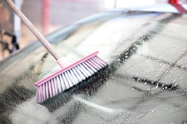 男人的手用粉红色的刷子刷着灰色的车。图片下载