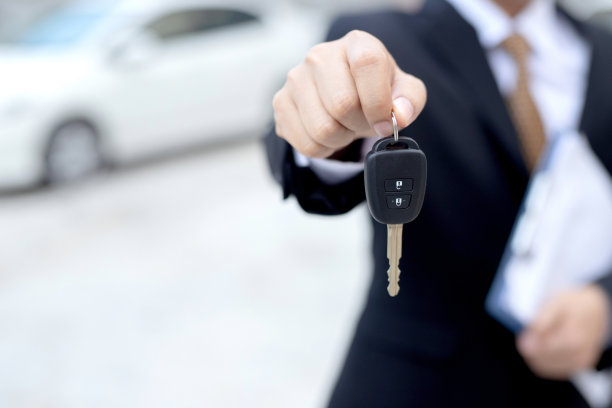 销售人员拿着车钥匙在展厅里以低利息交付给顾客。特别的促销活动图片下载