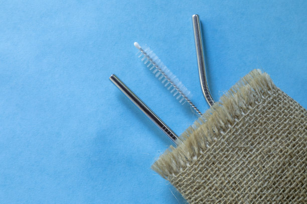 可重复使用的不锈钢吸管和清洁刷，蓝色背景，生态友好的生活方式，拷贝空间，俯视图，平面布局。图片下载