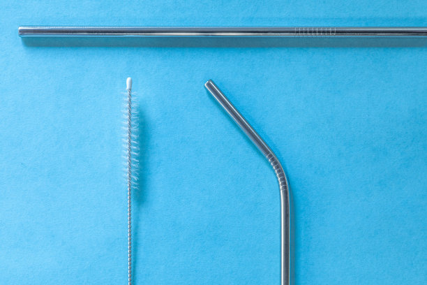 可重复使用的不锈钢吸管和清洁刷，蓝色背景，生态友好的生活方式，拷贝空间，俯视图，平面布局。图片下载