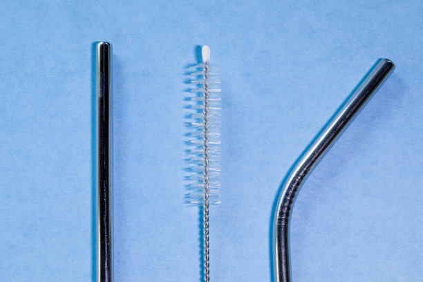 可重复使用的不锈钢吸管和清洁刷，蓝色背景，生态友好的生活方式，拷贝空间，俯视图，平面布局。图片下载