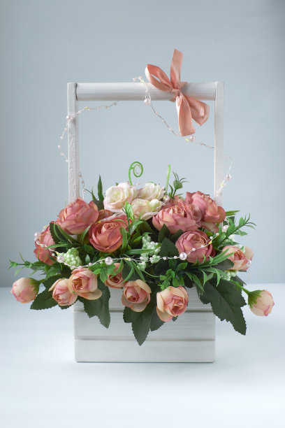 白色的篮子和一束粉红色的手工玫瑰。木制把手上的粉色蝴蝶结图片下载