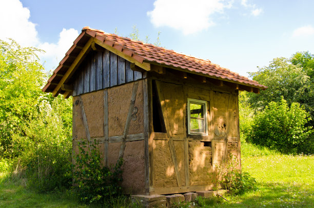 一个用壤土砖砌成的小棚子，在蓝天下的夏天，在一个古老的花园里图片下载