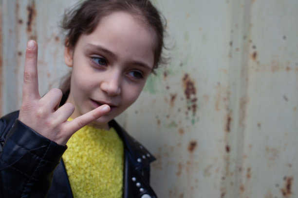 一个穿着摇滚夹克的小女孩做了一个“然后摇滚”的手势图片下载