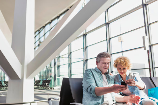 一名成熟男子在机场等飞机时向妻子展示智能手机的照片图片下载