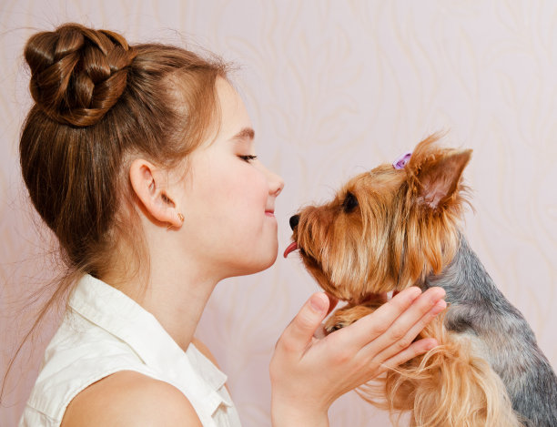 可爱的微笑的小女孩的孩子，青春期前抱着和玩的宠物狗图片下载
