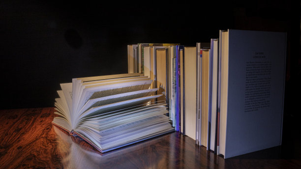 在昏暗的光线下，旧桌子上的一堆书。图片下载