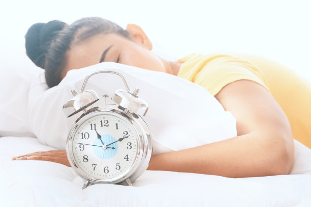 女人熟睡在床上，闹钟快中午了。图片下载