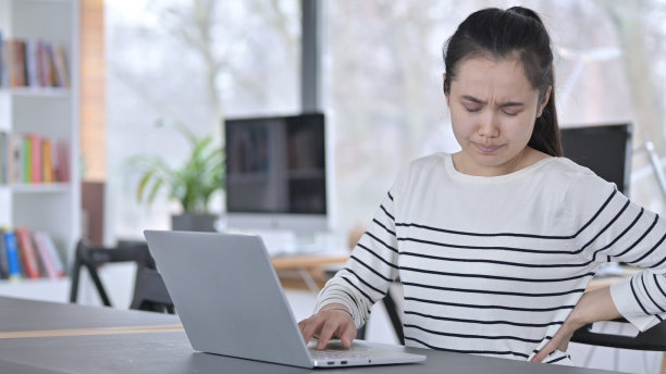 年轻的亚洲女性在办公室使用笔记本电脑时背痛图片下载