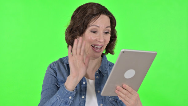 老妇人的平板电脑视频聊天，绿色背景图片下载