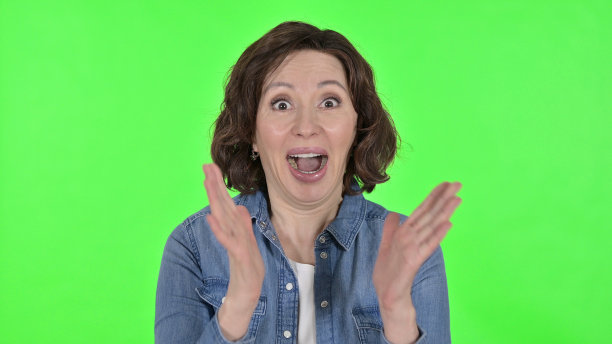 兴奋的老妇人庆祝在绿色色彩的关键背景图片下载