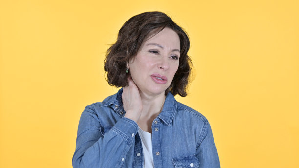 黄色背景上颈部疼痛的老妇人图片下载