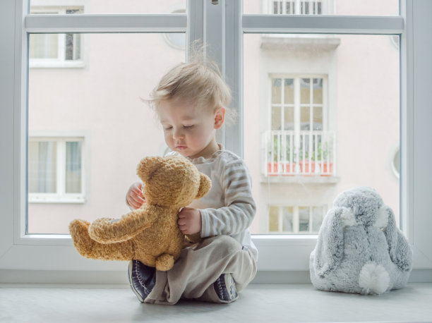 可爱的男孩在家看窗户，玩他的玩具图片下载