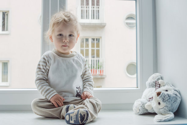 可爱的男孩在家看窗户，玩他的玩具图片下载
