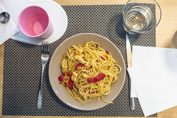 家用玻璃和刀叉将带胡椒的意大利面盛在棕色的盘子里图片下载