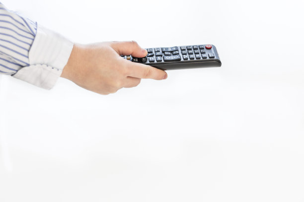 年轻女子的手拿着电视遥控器图片下载