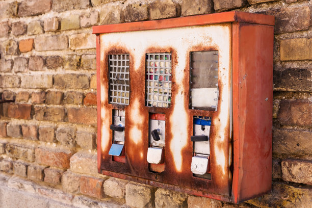 砖墙边生锈的古董口香糖机图片下载