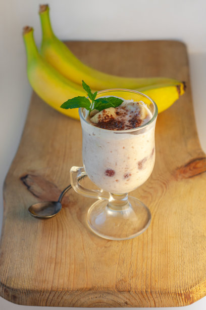 酸奶果冻甜点与香蕉，草莓，可可，新鲜薄荷在一个玻璃切板。健康的素食甜果冻图片下载