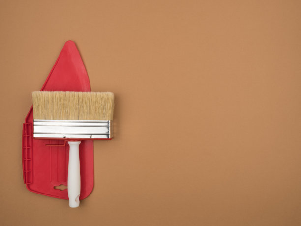 用于平滑墙纸的抹刀和一个大油漆刷。米色背景。图片下载