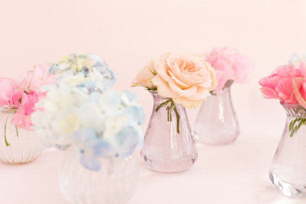 饰以盛开的蓝绣球花、香豌豆石竹、灌木玫瑰等装饰于粉红色背景的小水晶花瓶中。设计、创意。3月8日的国际妇女节和2月14日的情人节图片下载