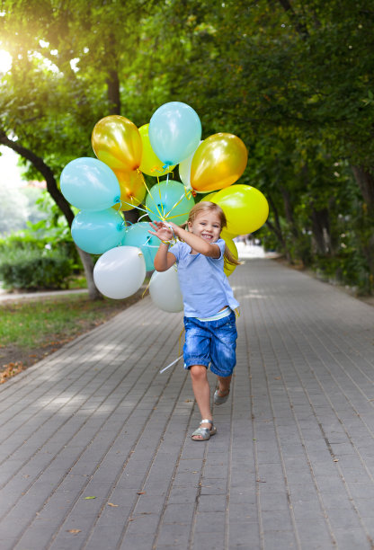 快乐的小女孩和一堆彩色的气球在奔跑图片下载