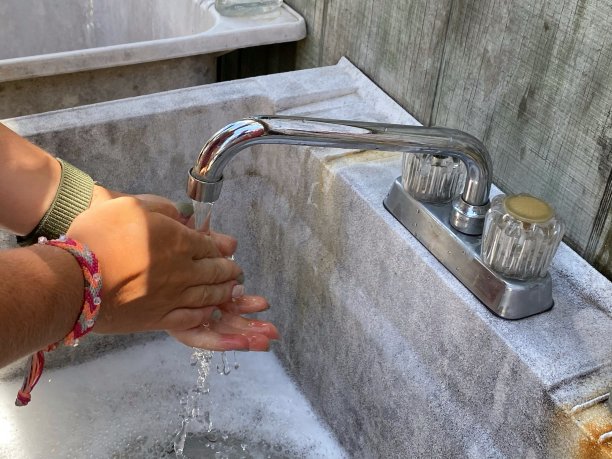 一个年轻人的特写镜头，女人，洗他的手在一个紫菜在夏天在院子里。预防冠状病毒疫情时，用肥皂水洗手。勤洗手保护。图片下载