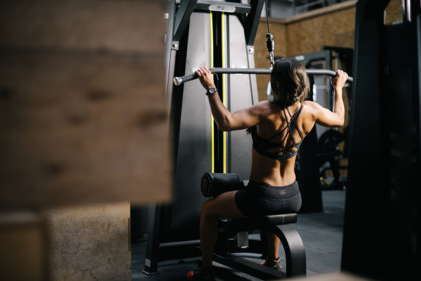 年轻女性健美运动员使用训练模拟器来锻炼背部肌肉图片下载