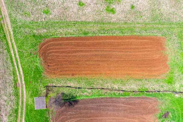 在村里种植蔬菜前的小空地上，有栅栏和谷仓。天线高度的观点。图片下载