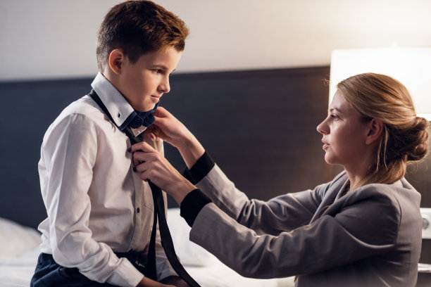 一张母亲在床上给儿子系领带的特写照片图片下载